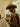 Person in brown hat and coat using tablet on subway, urban essentials look.