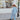 Person in a light blue outfit walking on a sidewalk with a store in the background