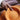Close-up of a hand holding an orange bowl with a blurred background