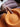 Close-up of a hand holding an orange bowl with a blurred background