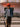 Person wearing a red hat and denim jacket standing in front of a store with neon signage.
