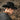 Person wearing a black wool felt fedora hat and dark jacket in a natural outdoor setting.