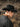 Person wearing a black wool felt fedora hat and dark jacket in a natural outdoor setting.