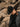 Person wearing a men’s black fedora hat and jacket against a rocky background.