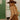 Woman wearing a brown hat and outfit in a tiled room.