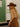 Woman wearing a brown hat and outfit in a tiled room.
