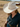 A woman in a denim shirt walks the ranch under soft sun, wearing a cream wool felt cowboy hat.